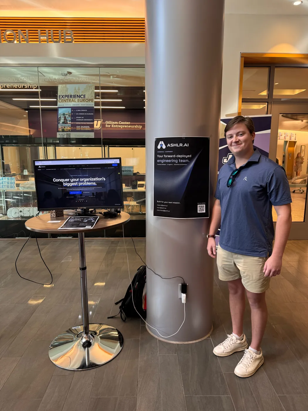 Mason Wyatt next to the Ashlr poster at the booth.